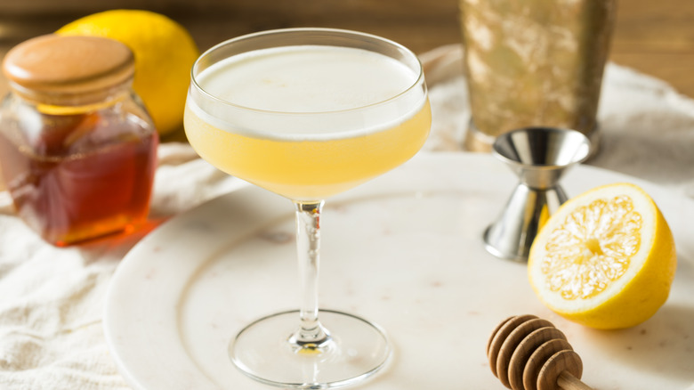 Cocktail on plate with lemon and jar of honey. 