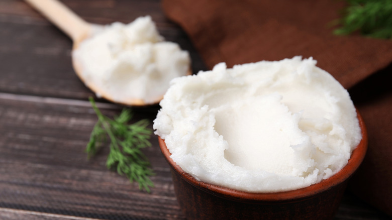 a bowl and spoonful of lard on a wooden table