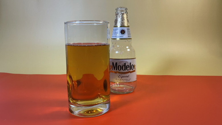 A glass of Modelo with an empty bottle next to it