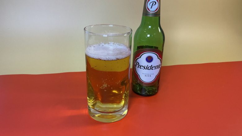 A glass of Presidente on a red background