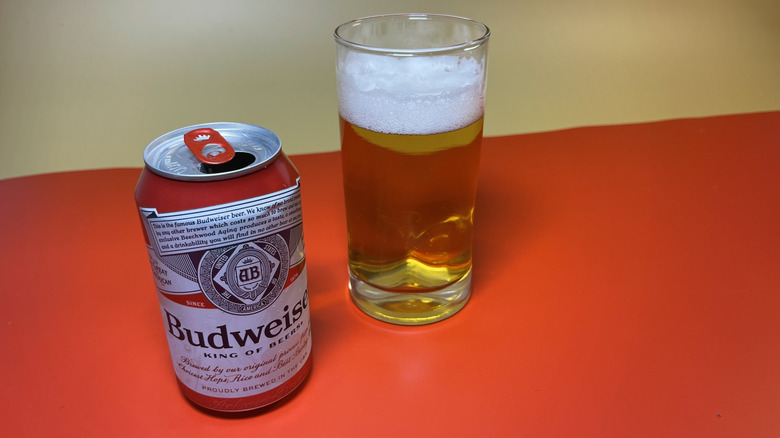 A can of Budweiser next to a frothy glass