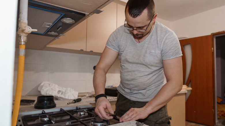 Person installing a gas stove in a kitchen