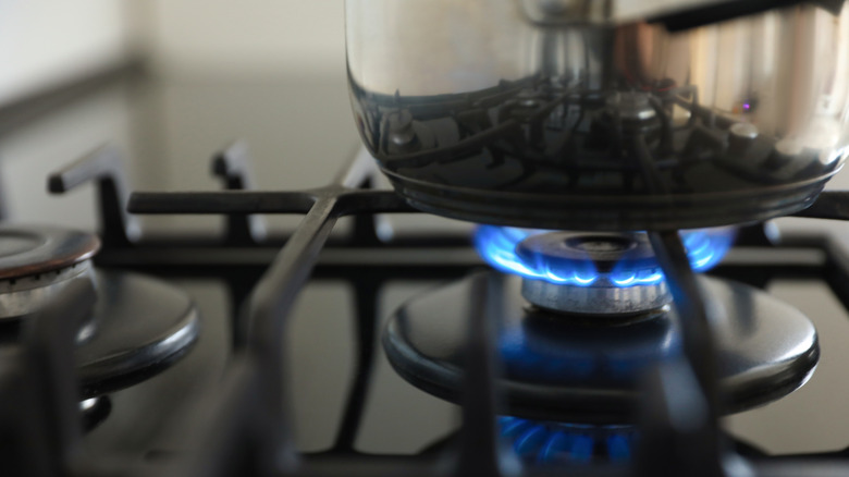 Gas stove with single burner on with a pot