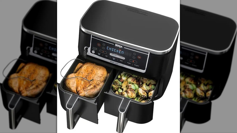 An air fryer with two baskets, one with chicken and the other with a veggie dish.
