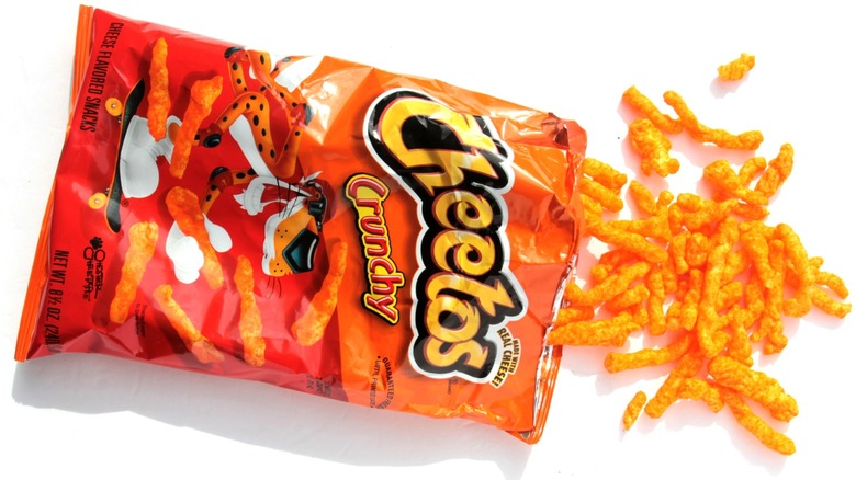 a top view of a bag of Cheetos on its side with Cheetos being poured on a white background