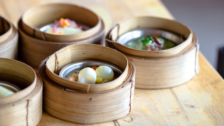 Various dim sum steamer baskets on a wooden table