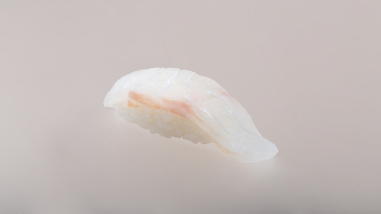 a piece of sea bass nigiri with grey background