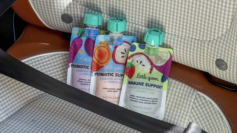 Three LittleSpoon smoothie pouches buckled into a seat