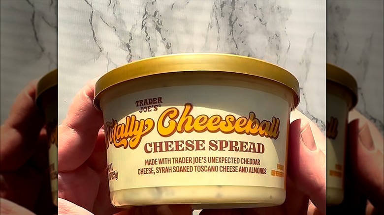 Hands holding a container of Trader Joe's Totally Cheeseball Cheese Spread