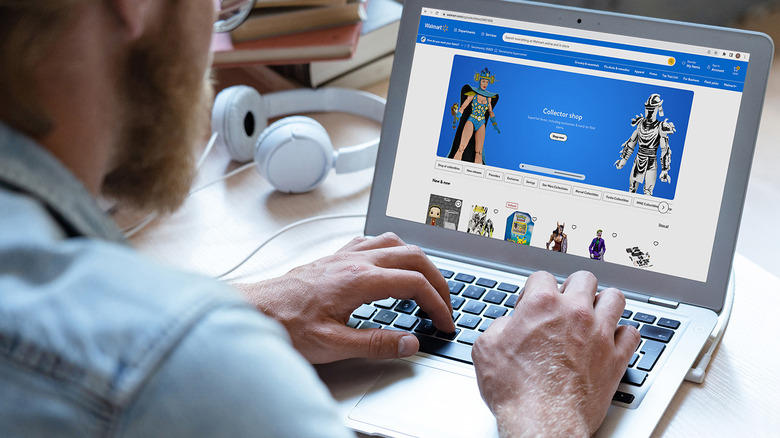 Bearded man in light blue denim shirt browses Walmart's collector shop on his laptop