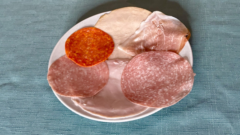 An array of six deli meats on a plain white plate