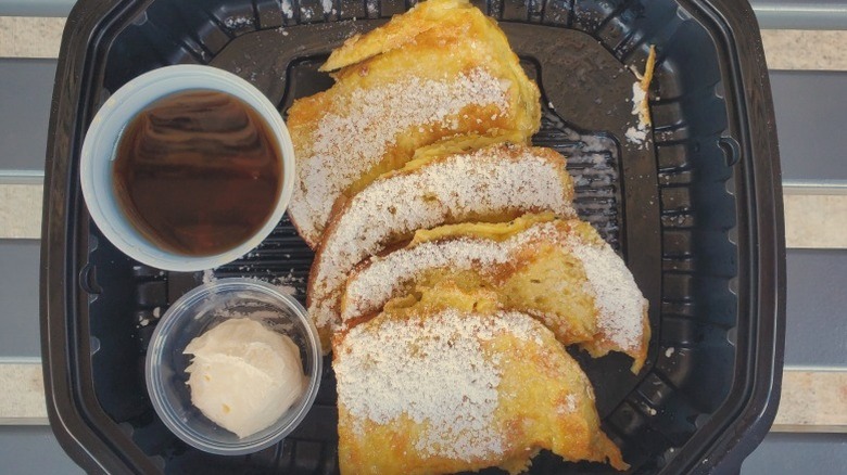 Original Pancake House French toast with butter and syrup in a black plastic container