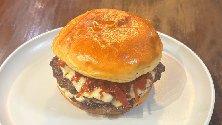 Wahlburgers pepperoni burger on a white plate on a wooden table