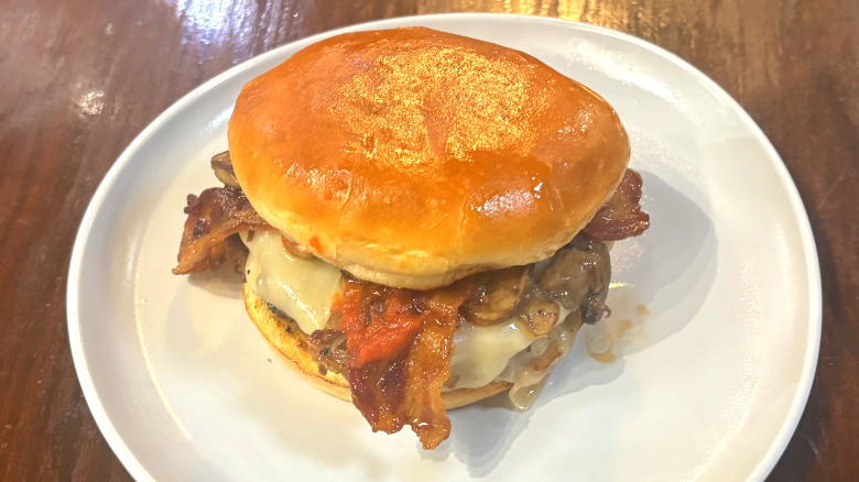 Wahlburgers O.F.D. burger on a white plate on a wooden table