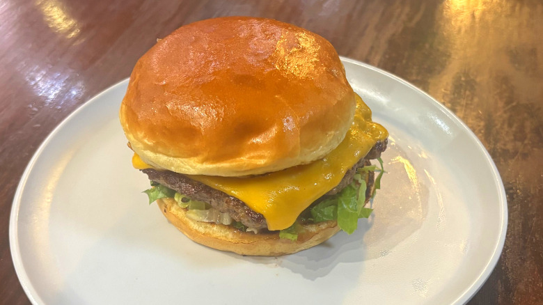 Wahlburgers our burger on a white plate on a wooden table