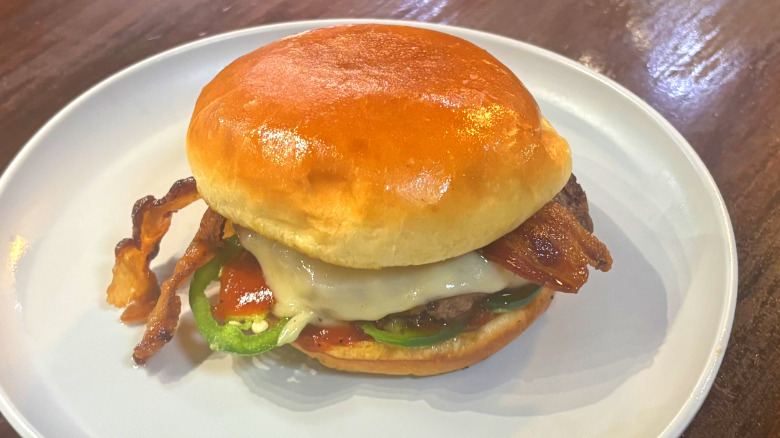Wahlburgers BBQ bacon burger on a white plate on a wooden table