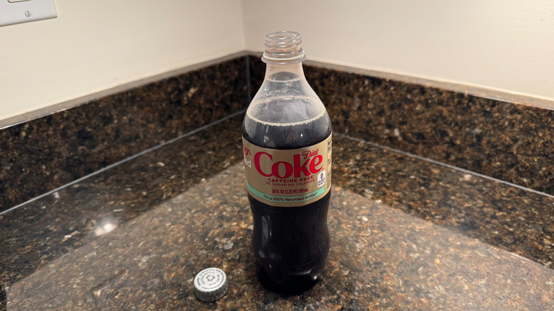 A bottle of Caffeine-free Diet Coke on a countertop with the lid removed