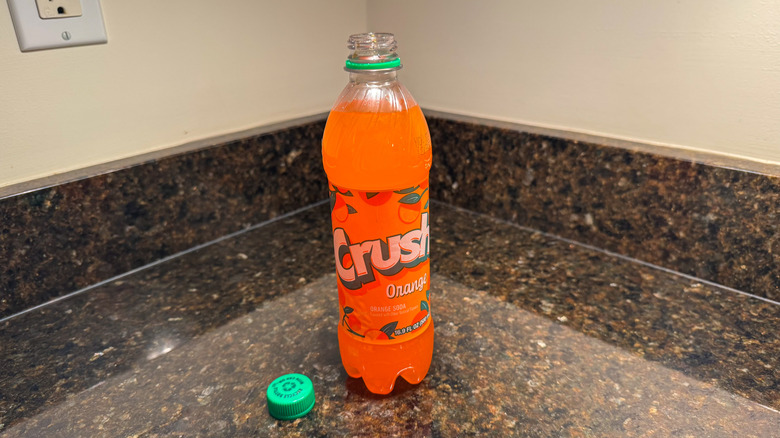 A bottle of crush orange soda on a counter with the lid removed