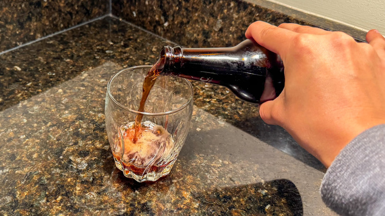 The author pouring a glass of root beer soda from a glass bottle