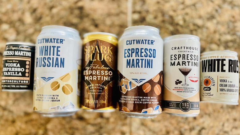 Various canned coffee cocktails laying down on a marble counter