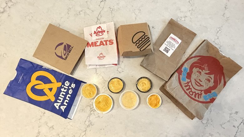 A lineup of chain restaurant cheese sauces surrounded by their packages