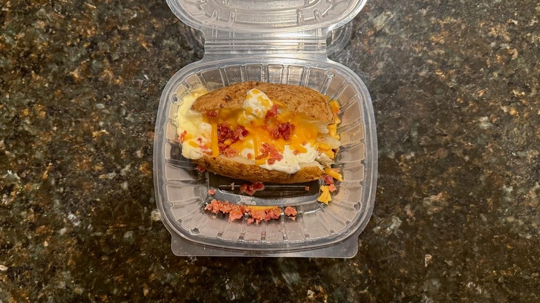 Takeout container with Ruby Tuesday loaded baked potato on black table