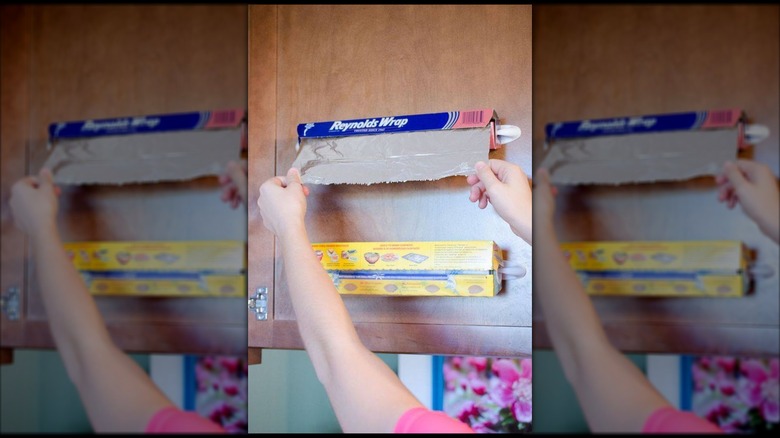 Foil and plastic wrap containers hung on the side of a cabinet with Command hooks