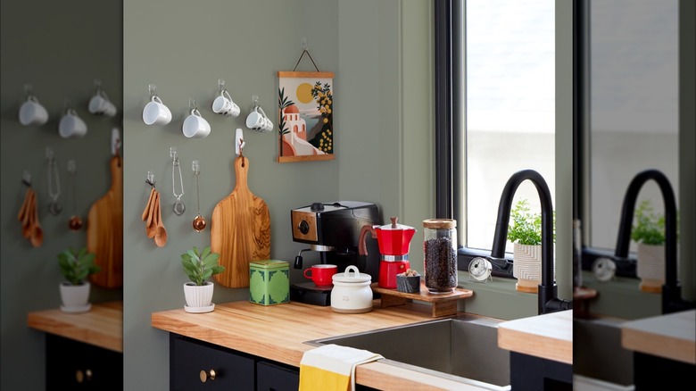Teacups, coffee mugs, and a cutting board hung on a kitchen wall with Command hooks