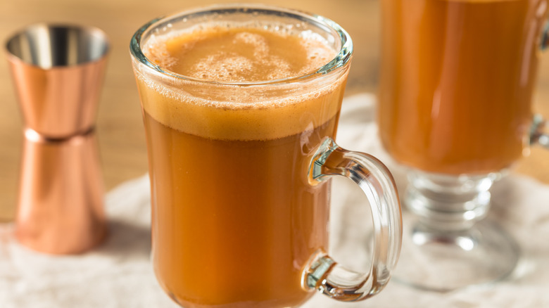 A clear mug filled with a hot buttered rum.