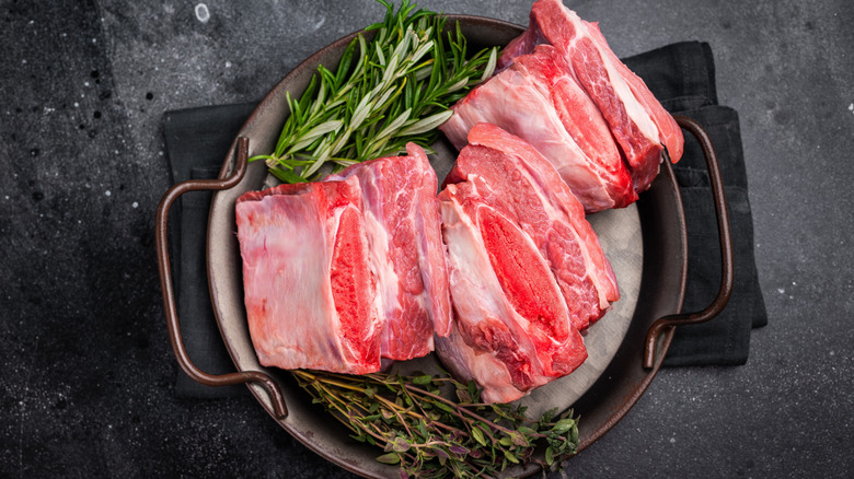 Short ribs on a metal tray with herbs.