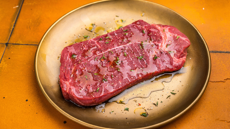 A raw sirloin steak on a gold plate.