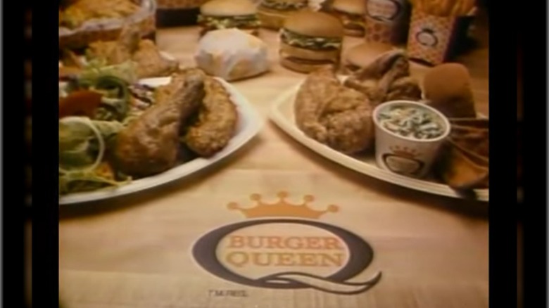 Image from Burger Queen commercial showing various meal platters surrounding a Burger Queen logo embossed on the table