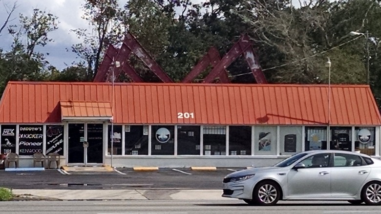 An old Milligan's restaurant with a silver car outside