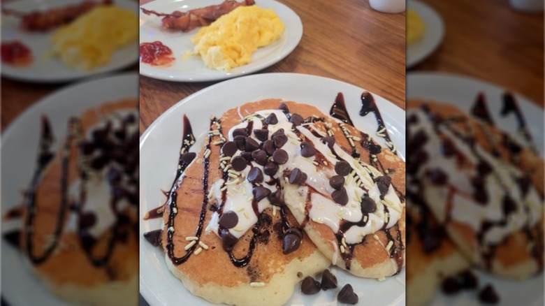 The Say It Three Times Slam meal from Denny's, with three pancakes covered with cream, chocolate sauce, sprinkles, and chocolate chips
