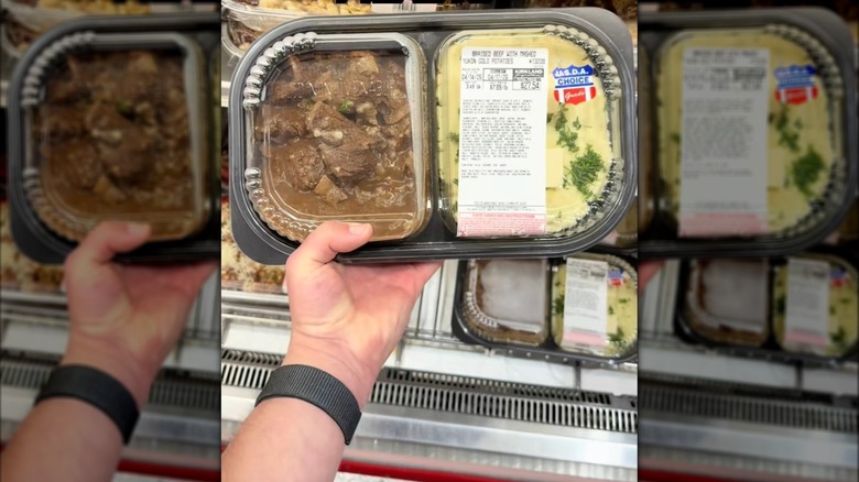 Hand holding package of braised beef and mashed potatoes at Costco