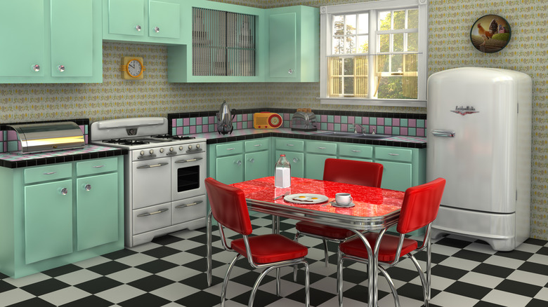 A classic retro kitchen with pastel green cabinetry and a red vinyl table and chairs.