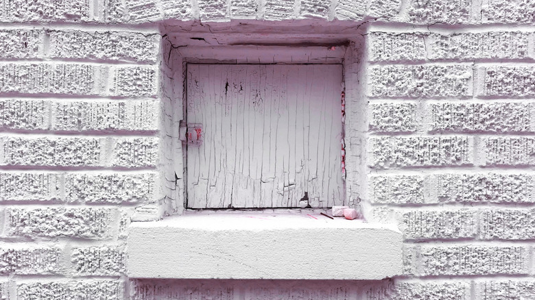 A vintage milk door on the side of a house painted white