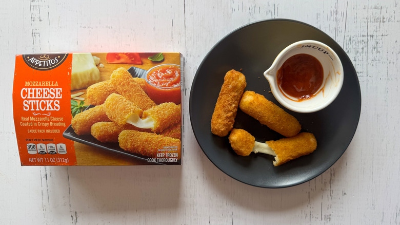 Appetitos mozzarella sticks on a plate with a cup of sauce next to package on a table