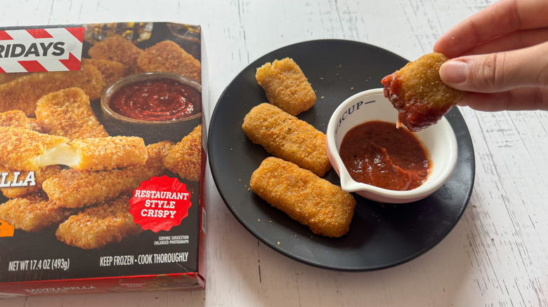 Hand dipping mozzarella stick into sauce