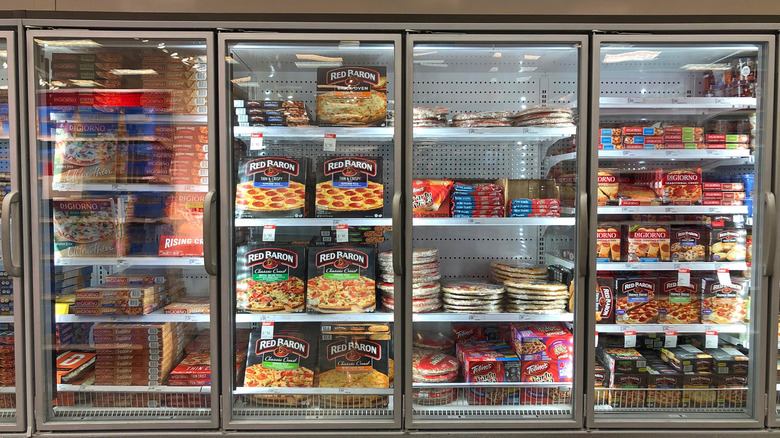 Frozen pizzas on display inside grocery store freezers