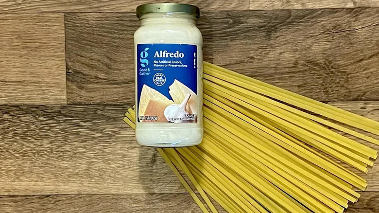 A jar of Good & Gather Alfredo Sauce with dried spaghetti noodles