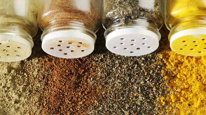 Various spice jars lying on tier side with the contents spilling out