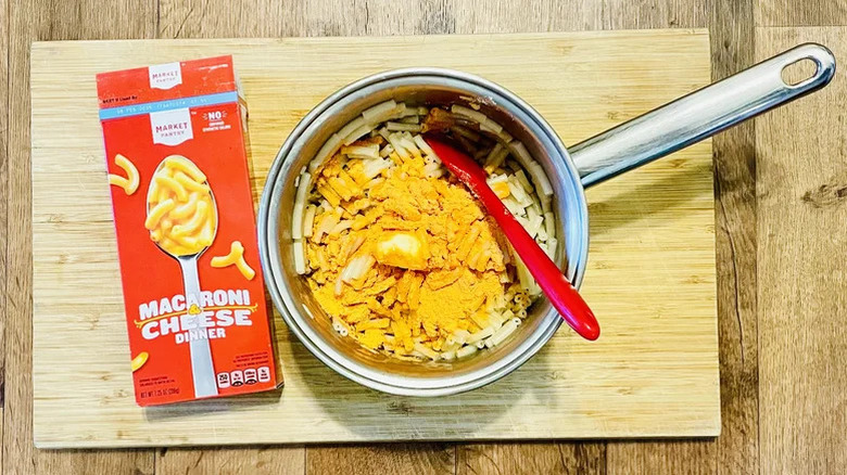 A box of Market Pantry Macaroni & Cheese with a pot containing the cooked contents