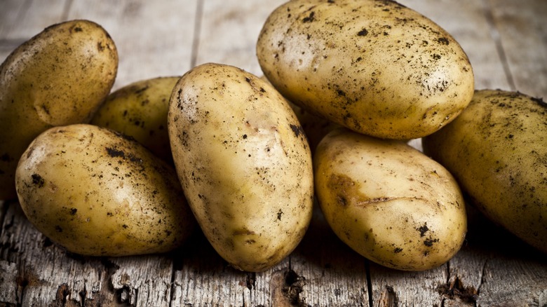 Unwashed potatoes on a rustic wooden platform