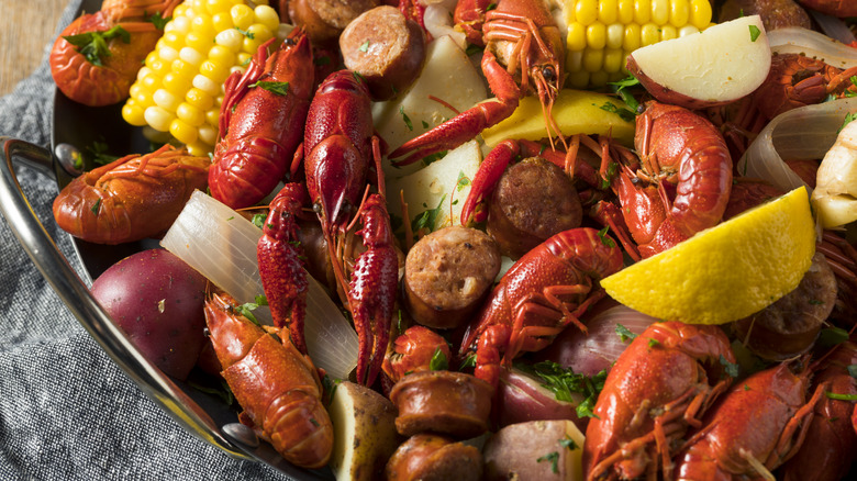 a close up picture of a seafood boil with crab, potatoes, corn, onion, sausage, and lemon