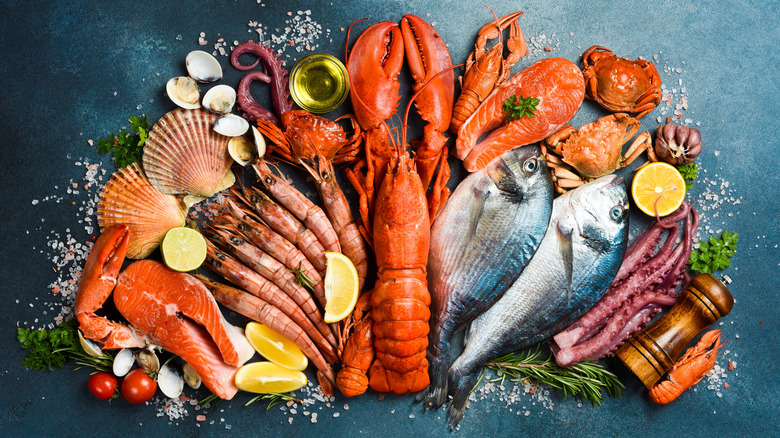 a close up of a variety of fresh seafood with spices and herbs on a black marble background