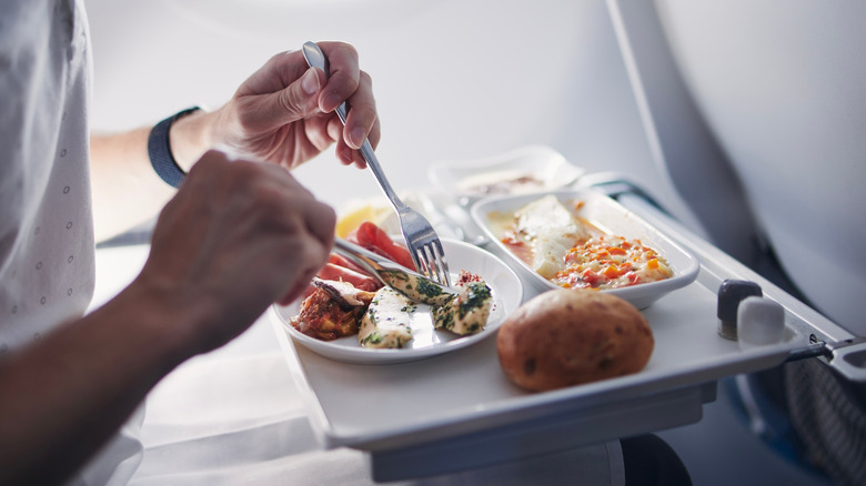 A passenger cutting up an in-flight meal