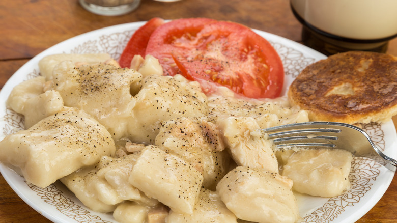 Plate of chicken and dumplings with tomato slices