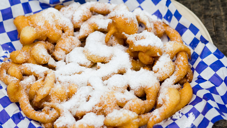 Dish of funnel cakes dusted in sugar on checkered paper