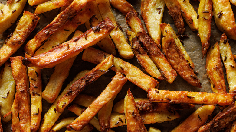 French fries with cumin seeds on parchment paper
